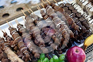 Different fruit sticks: Fresh strawberries,bananas covered with white and dark chocolate for sale on local market place