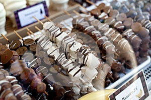 Different fruit sticks: Fresh strawberries,bananas covered with white and dark chocolate for sale on local market place in Vienna.