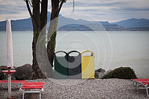 3 different garbage cans to separate garbage stand on the shore of Garda Lake photo