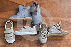 Different girl`s shoes on a wooden background