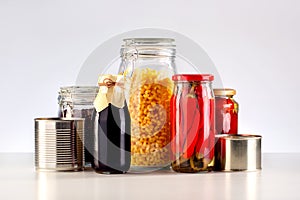 Different glass jars with grains, pasta, vegetable, cans of canned food