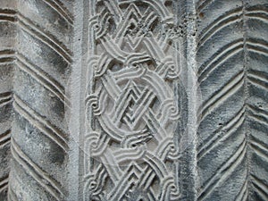 Different graven sculptures in a wall of a church in Armenia.