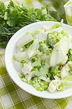 Different green and white, fresh, raw vegetables in the white bowl