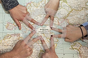 Different hands drawing a star pointing Europe in a world map