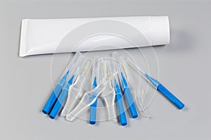 Different interdental brushes against the toothpaste tube on gray surface