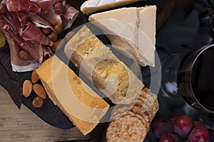 Different Italian cheese and prosciutto, appetizers for a party and red wine. Copy space. Flat lay