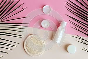 Different jars of body and face cream on a pastel pink-beige background. Beauty and cosmetic concept. Top view, flat lay