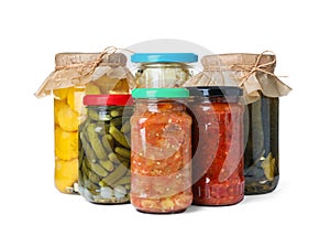 Different jars with pickled vegetables on background