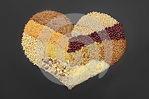 Different kind of cereals, grain and seeds, setting in the heart shape on black background.