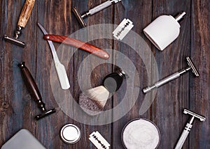 Different kind of razors safety and straight,  blade, brush and perfume on a wooden background.  View from the top.