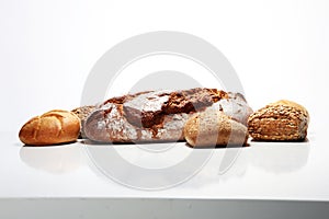 Different kinds of bread and bread rolls on board from above