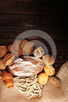 Different kinds of bread and bread rolls on board from above