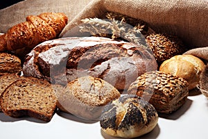 Different kinds of bread and bread rolls on board from above