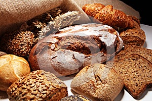 Different kinds of bread and bread rolls on board from above