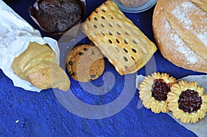 Different kinds of bread rolls on black board from above. Kitchen or bakery poster design. muffin, croissant, cookies