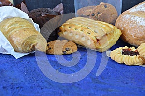 Different kinds of bread rolls on black board from above. Kitchen or bakery poster design. muffin, croissant, cookies