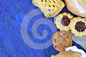 Different kinds of bread rolls on black board from above. Kitchen or bakery poster design. muffin, croissant, cookies