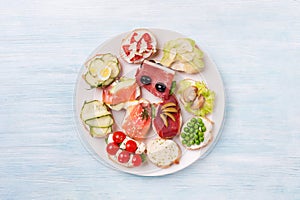 Different kinds canapes in plate on the wooden background