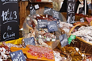 Different kinds of French salami provencale presented in wicker baskets with handwritten chalk boards on farmer market