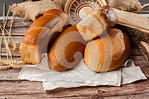 Different kinds of fresh bread as background, top view. Bakery gold rustic crusty loaves of bread and buns on wooden background.