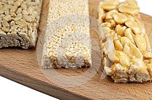 Different kinds of kozinaks on wooden Board on white isolated background, kozinak sunflower peanut sesame, Oriental sweets