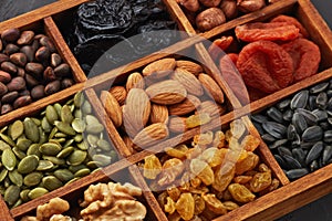 Different kinds of nuts, dried fruits in wooden box. Healthy food. Top view. Vegetarian nutrition