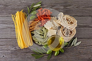 Different kinds of of pasta on the wooden background. Spaghetti. Olive oil.