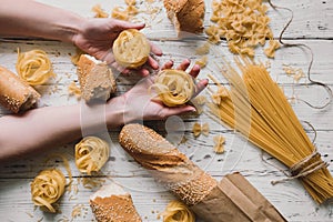 Different kinds of pasta on wooden table, bread