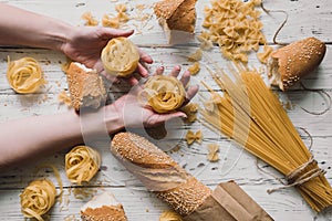 Different kinds of pasta on wooden table, bread