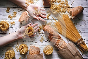 Different kinds of pasta on wooden table, bread