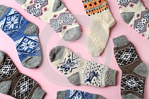 Different knitted socks on pink background. Winter clothes