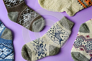 Different knitted socks on violet background. Winter clothes