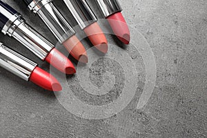 Different lipsticks and space for text on grey, flat lay