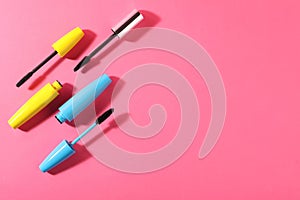 Different mascaras on bright pink background, flat lay. Space for text