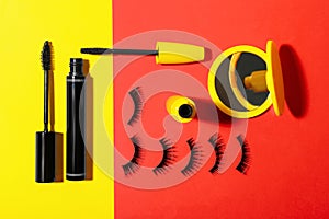 Different mascaras, fake eyelashes and mirror on color background, flat lay. Makeup product