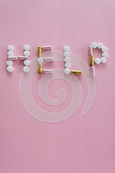 Different medication pills in HELP word shape on pink background. Healthcare, medical concept