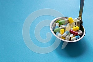 Different medicines in a big spoon on a blue background