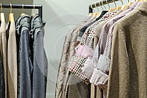 Different men's wear (jackets, shirts, sweaters) on wooden hangers