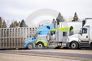 Different model of big rigs semi trucks with different semi trailer stand on truck stop parking place