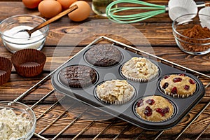 Different Muffins in bakeware or muffin pan on broun wooden background. Basic muffin recipe. Homemade muffins for breakfast or des