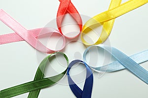 Different multi colored awareness ribbons on white background photo