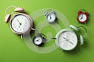 Different multicolor alarm clocks on green background