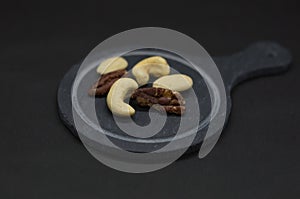 Different Nuts on a plate in front of black Background