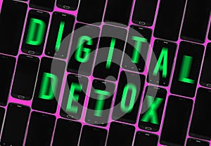 Different off black smartphones with green blurred text digital detox, tilted words, pink background