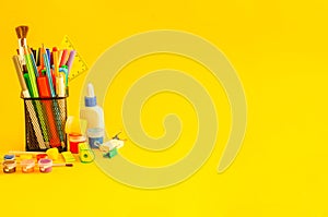 Different office supplies in a cup on a yellow background with a place for text