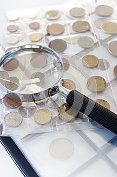 Different old collector`s coins with a magnifying glass