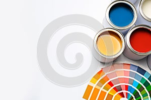 Different paint cans and color palette on white background, top view.