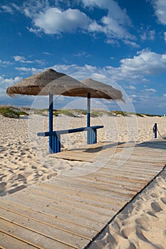Different parasols and sun loungers on the empty beach on Tavira island, Algarve. Portugal