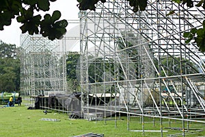 Different parts of metal scaffold on the construction field. Workers build a concert stage. Stage equipment