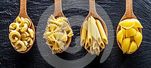 Different pasta types in wooden spoons on the table. Top view.